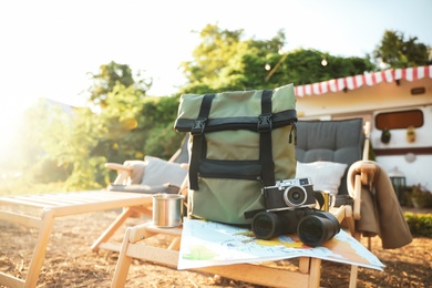 Photo of Green backpack and travel accessories on deck chair outdoors. Summer trip
