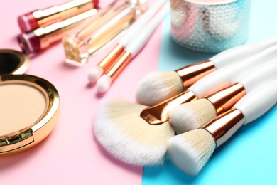 Photo of Professional makeup brushes and different decorative cosmetics on color background