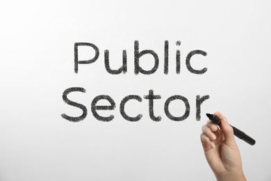 Woman writing phrase PUBLIC SECTOR on glass against white background, closeup