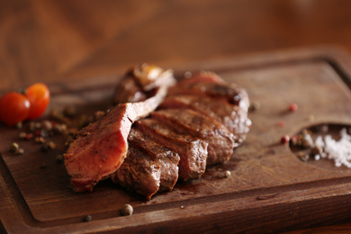 Tasty roasted meat served on wooden table, closeup. Cooking food