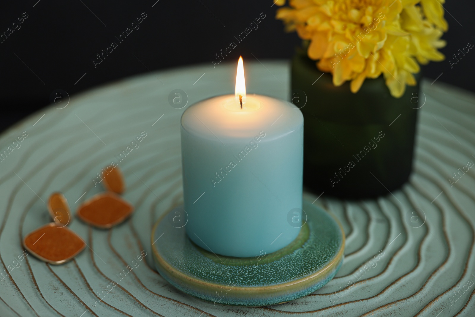 Photo of Side table with candle, flowers and earrings in room, closeup