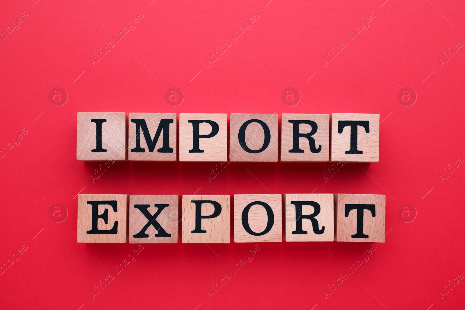 Photo of Words Import and Export made of wooden cubes with letters on red background, top view