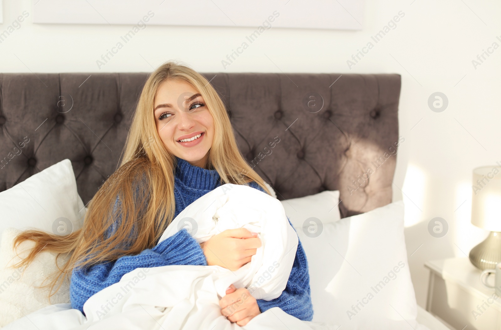 Photo of Beautiful young woman sitting in bed at home. Winter atmosphere