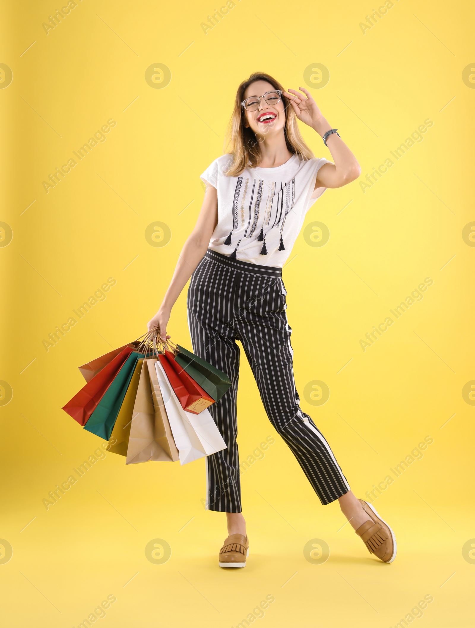 Photo of Beautiful young woman with shopping bags on color background