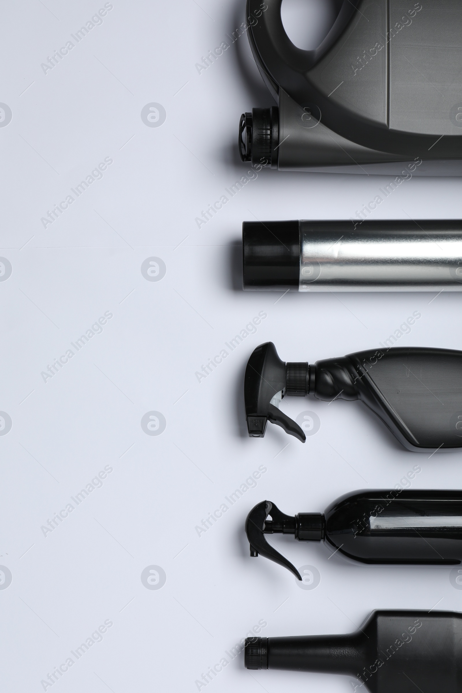 Photo of Black bottles and canister on white background, flat lay. Space for text