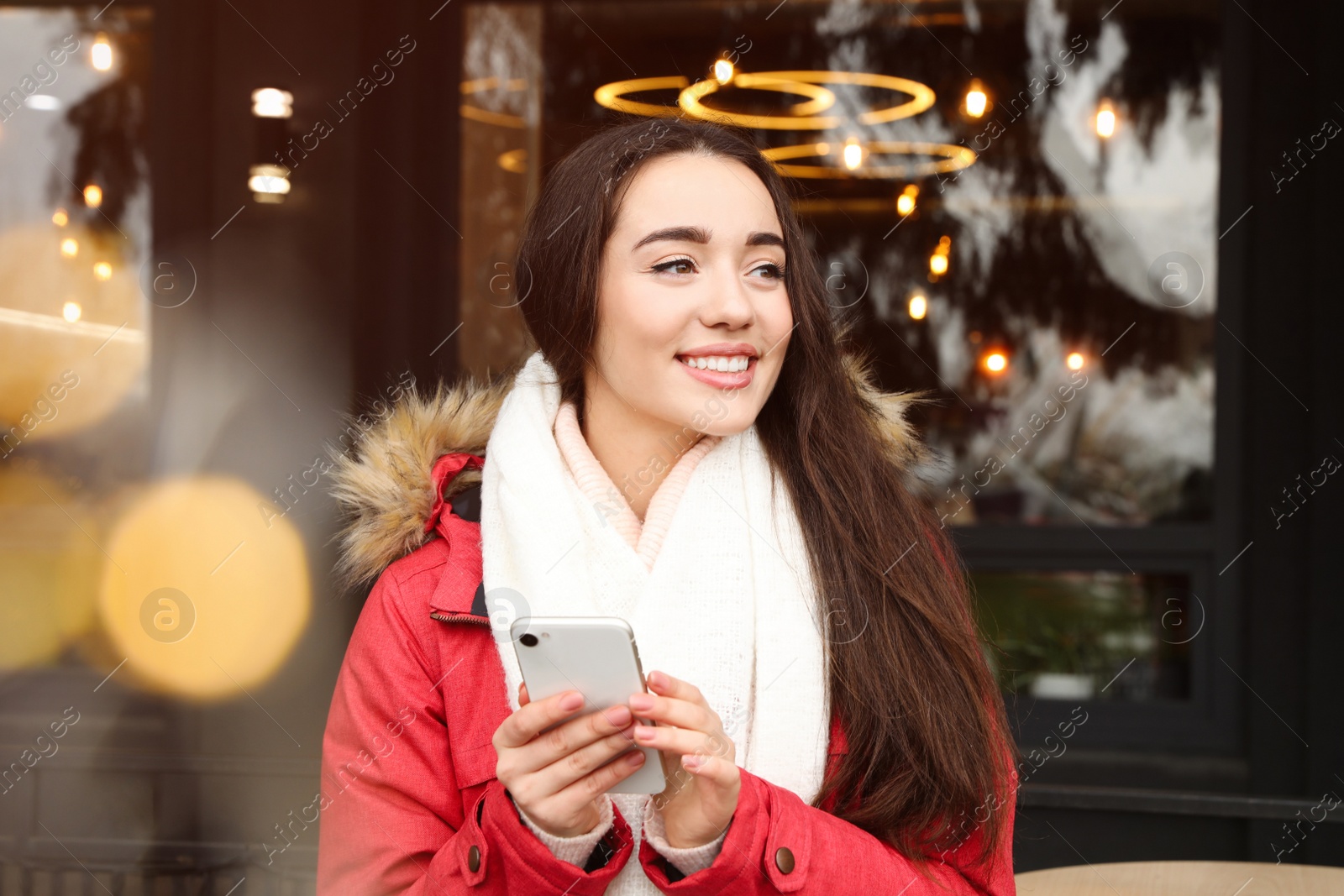 Photo of Young woman with smartphone at winter fair. Christmas celebration