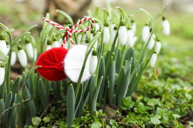 Traditional martisor and beautiful snowdrops outdoors, closeup. Symbol of first spring day