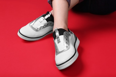 Woman in stylish shoes sitting on color background