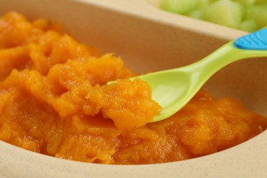 Photo of Healthy baby food. Section plate with delicious pumpkin puree, closeup