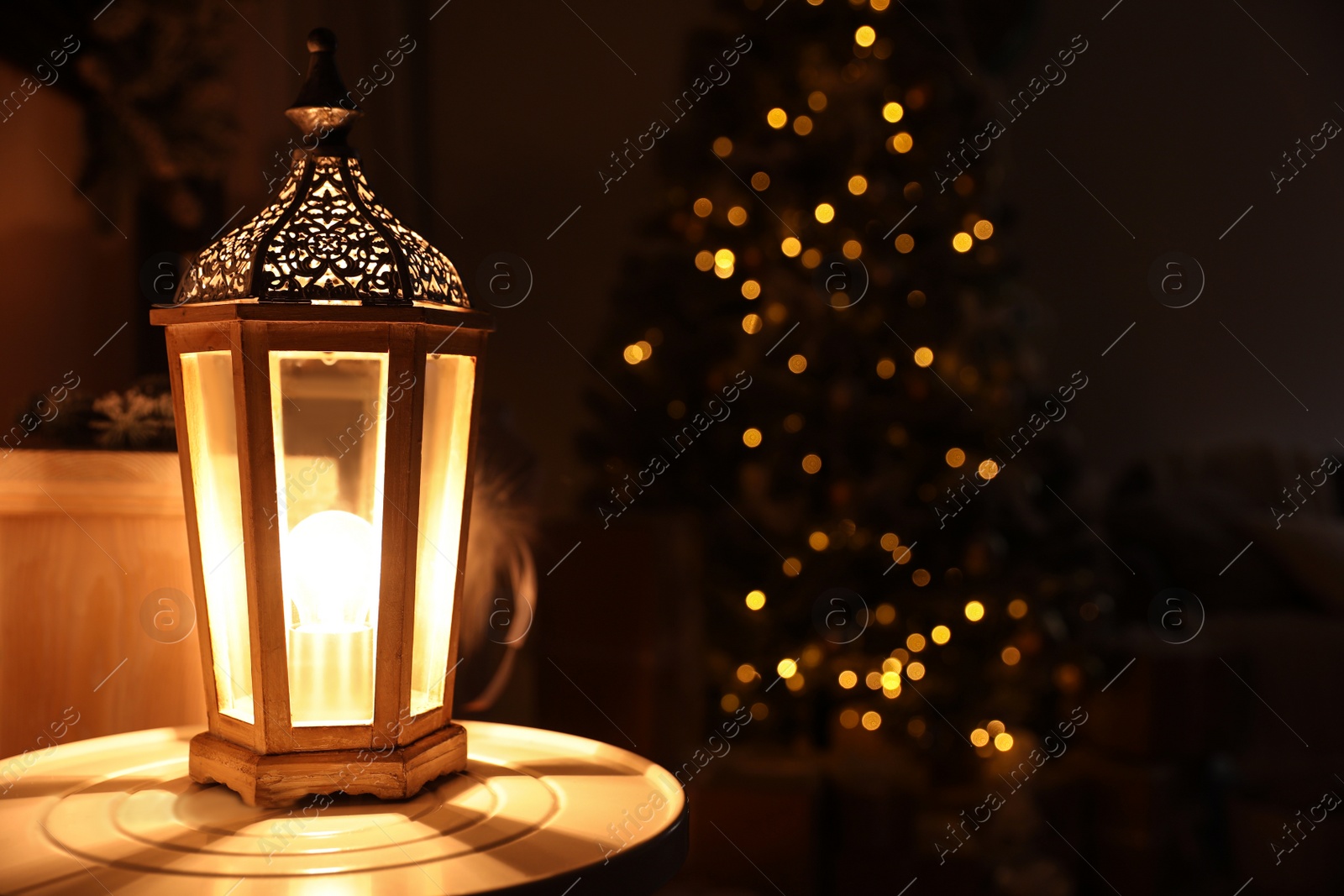 Photo of Decorative lantern on table against festive lights. Stylish Christmas interior