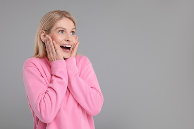 Photo of Portrait of happy surprised woman on grey background, space for text