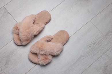 Photo of Pair of soft slippers on wooden floor, top view. Space for text