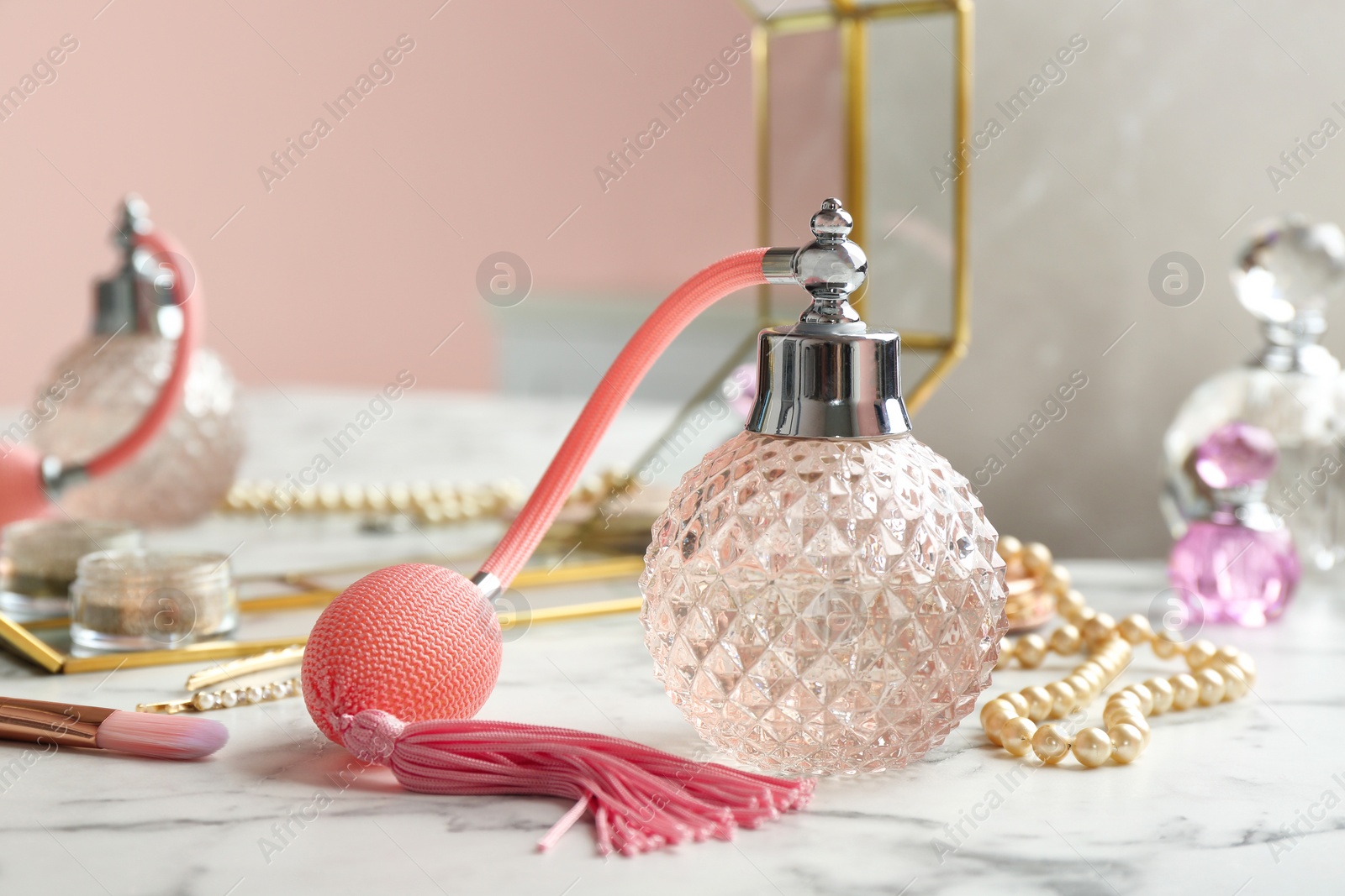 Photo of Vintage crystal bottle of luxurious perfume and jewelry on white marble table