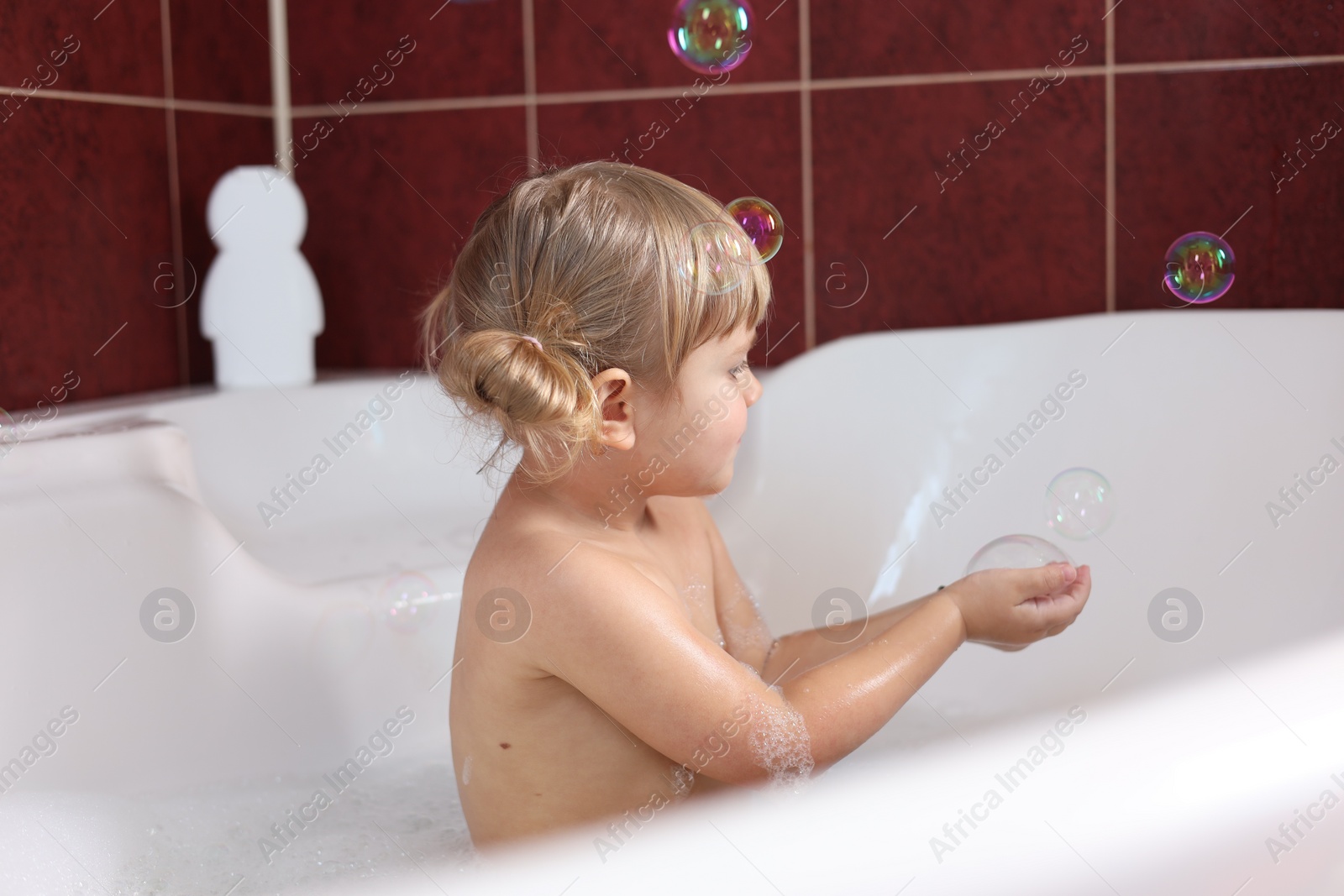 Photo of Little girl having fun in bathtub at home