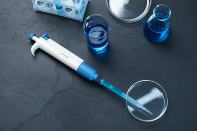 Laboratory analysis. Micropipette, petri dishes, beaker and flask on black table, above view