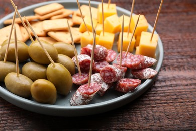 Toothpick appetizers. Pieces of sausage, olives and cheese on wooden table