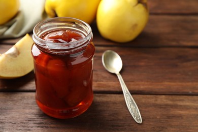 Photo of Tasty homemade quince jam in jar on wooden table, closeup. Space for text