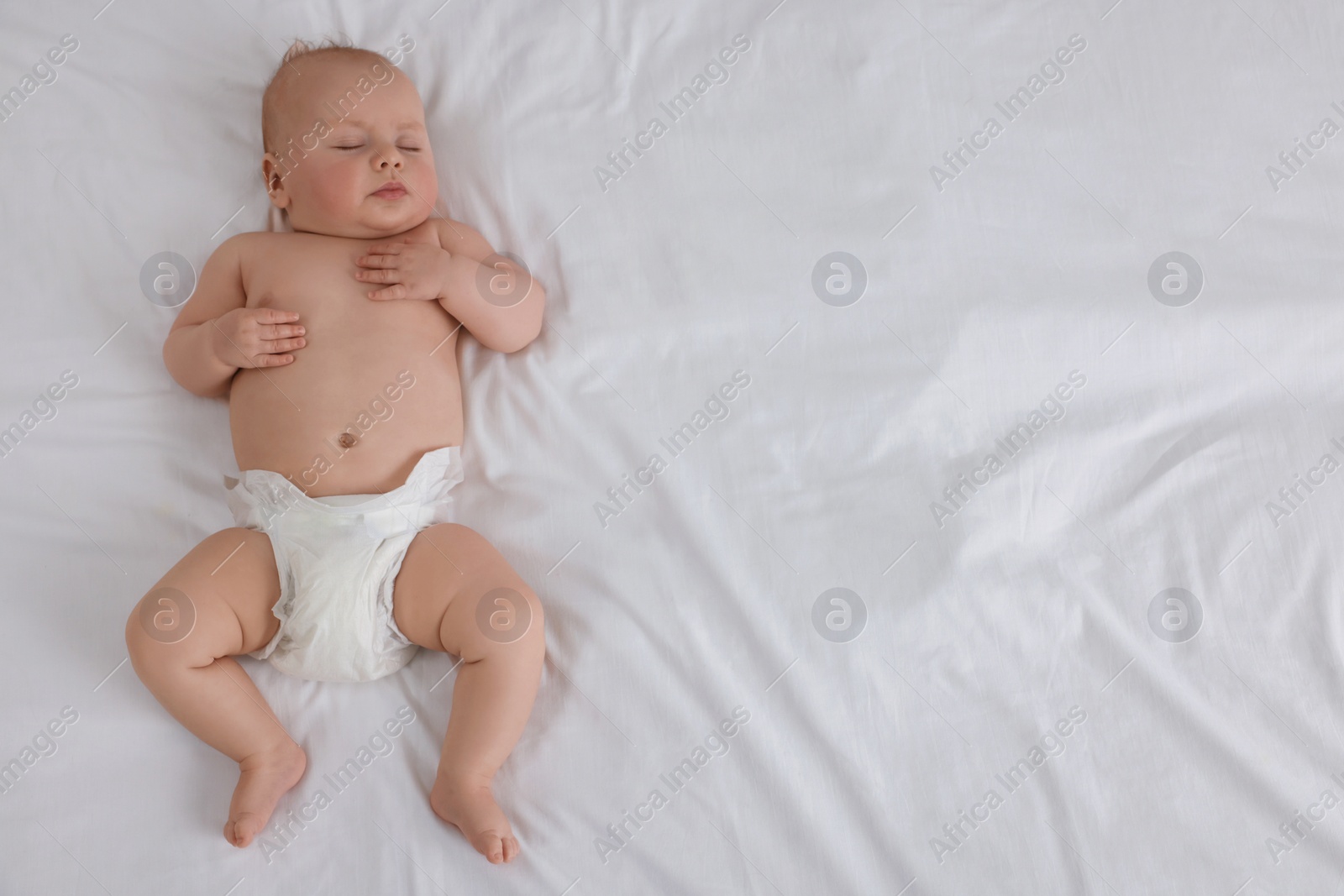Photo of Cute newborn baby in diaper sleeping on bed at home, top view. Space for text
