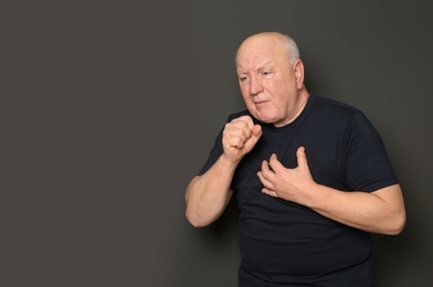 Photo of Senior man suffering from cough on dark background. Space for text