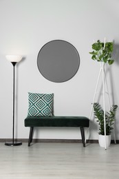 Photo of Stylish round mirror on white wall over bench in room