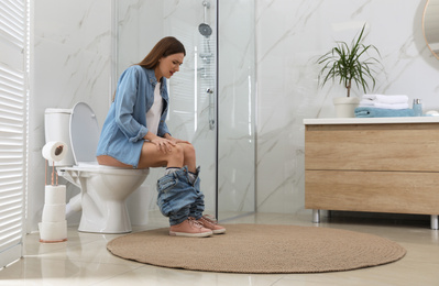 Woman suffering from hemorrhoid on toilet bowl in rest room