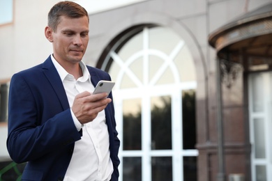 Photo of Businessman with modern smartphone on city street