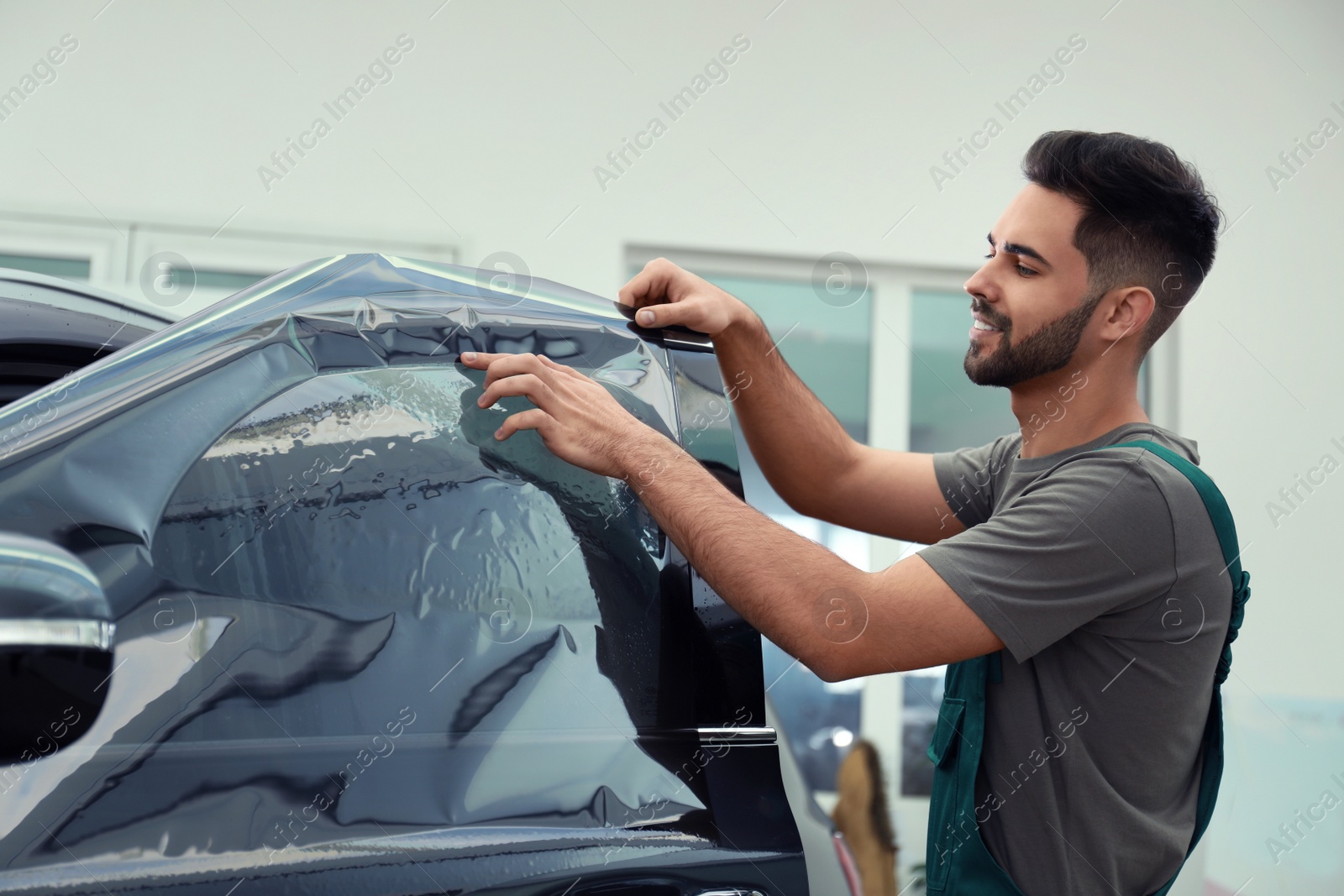 Photo of Worker tinting car window with foil in workshop