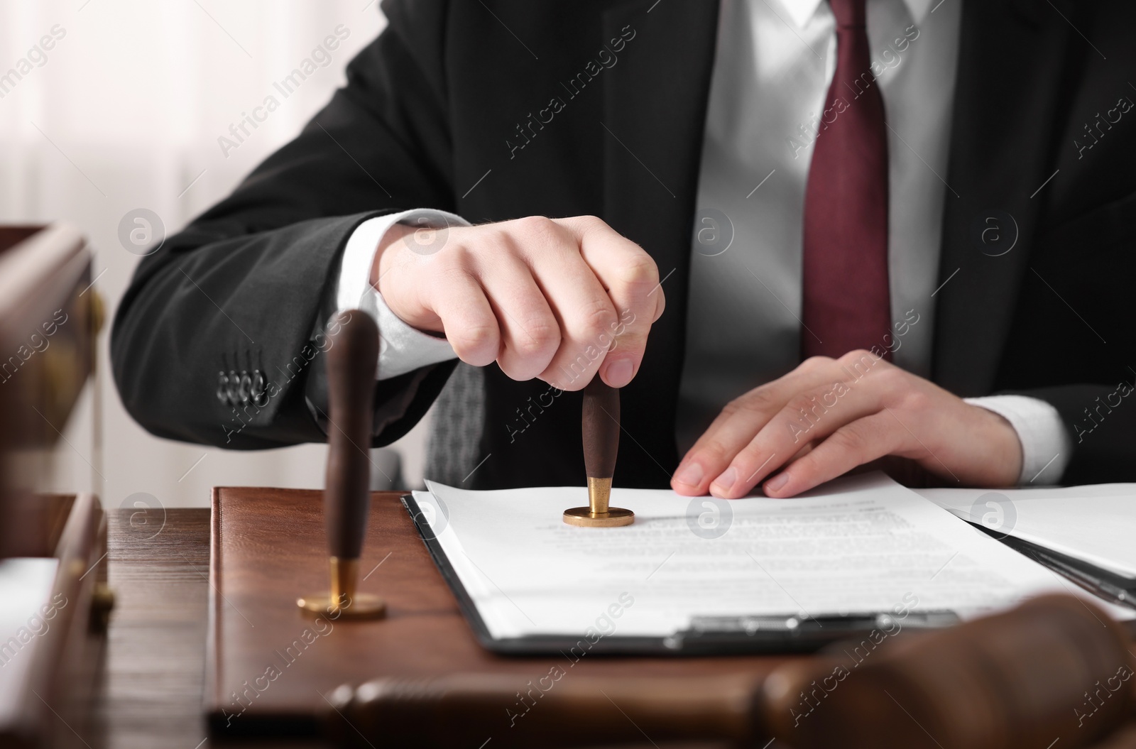 Photo of Notary stamping document at wooden table in office, closeup