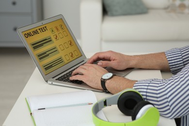 Man taking online test on laptop at desk indoors, closeup