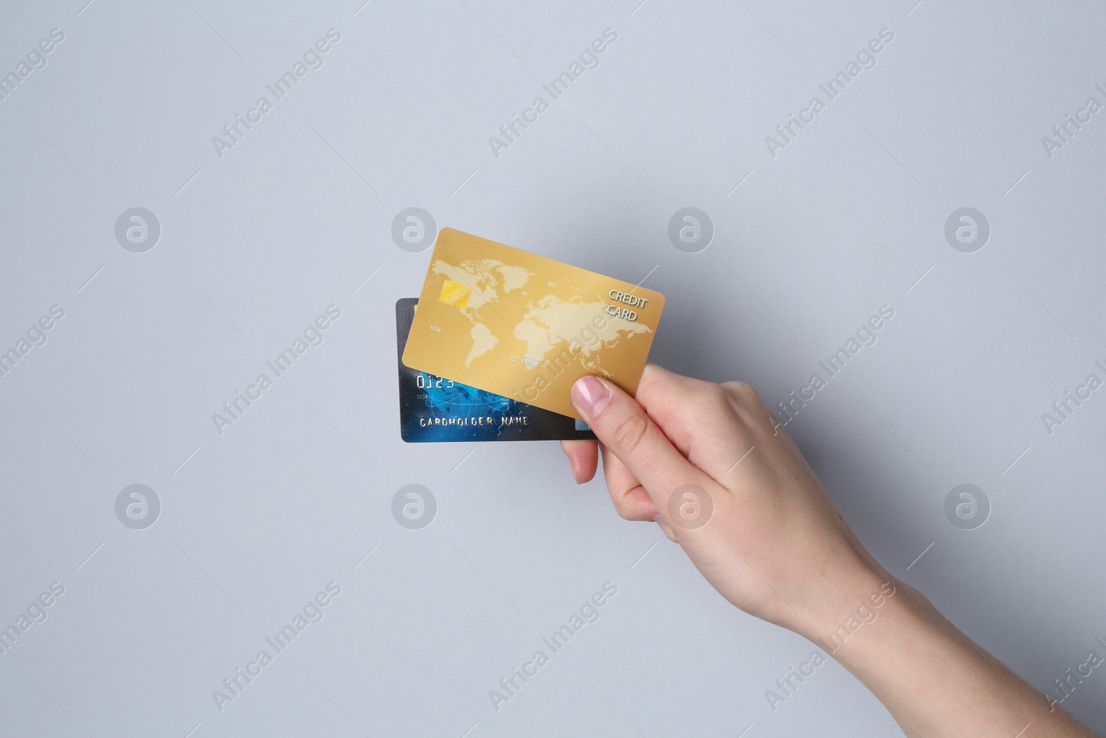 Photo of Woman holding credit cards on light grey background, closeup