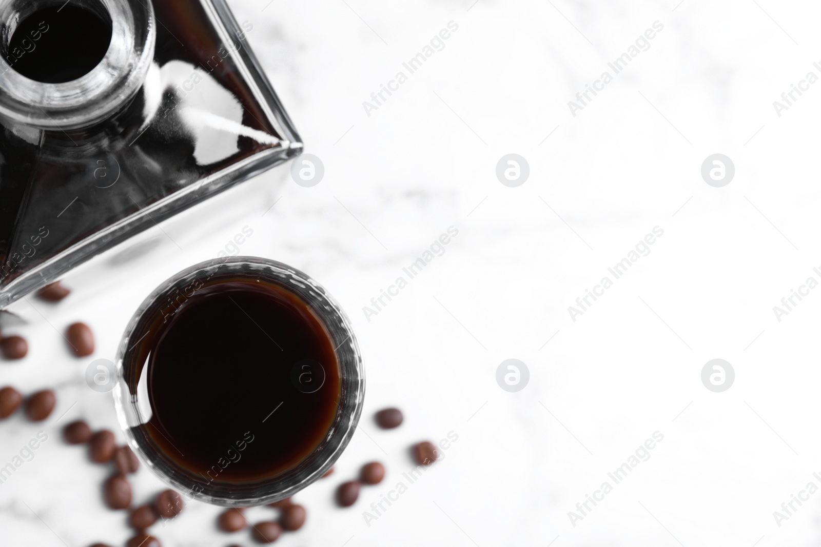 Photo of Coffee liqueur and beans on white table, flat lay. Space for text