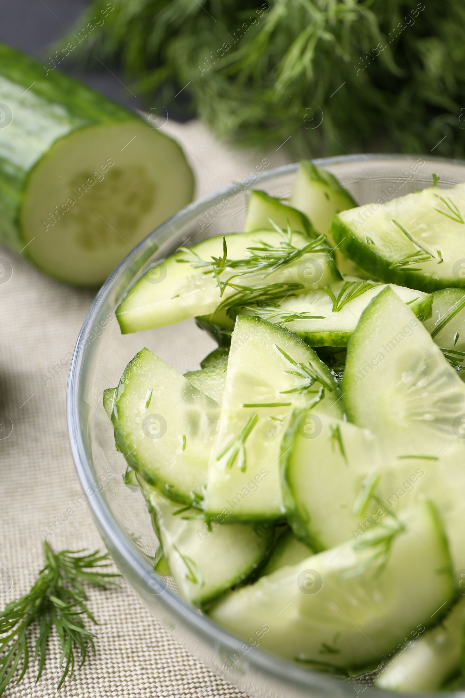 Photo of Cut cucumber with dill in glass bowl on table, closeup