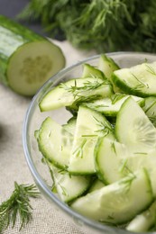 Photo of Cut cucumber with dill in glass bowl on table, closeup