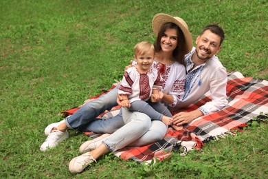 Photo of Happy family in Ukrainian national clothes on green grass outdoors