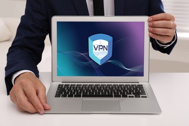 Image of Man with modern laptop with switched on VPN at white table indoors, closeup
