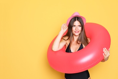 Sexy young woman in bikini with inflatable ring on color background