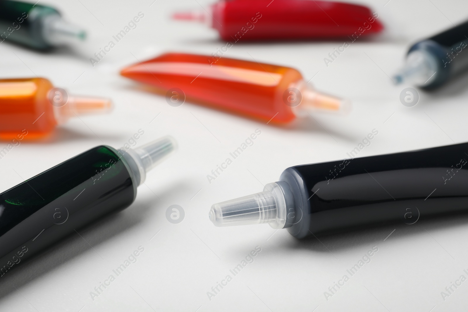 Photo of Tubes with different food coloring on white background, closeup