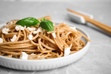 Tasty buckwheat noodles with chopsticks on light grey table, closeup