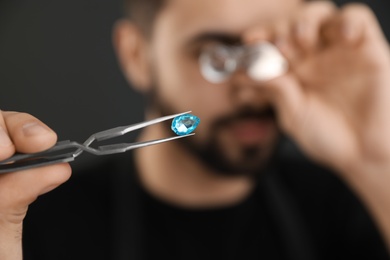 Photo of Male jeweler evaluating gemstone in workshop, closeup