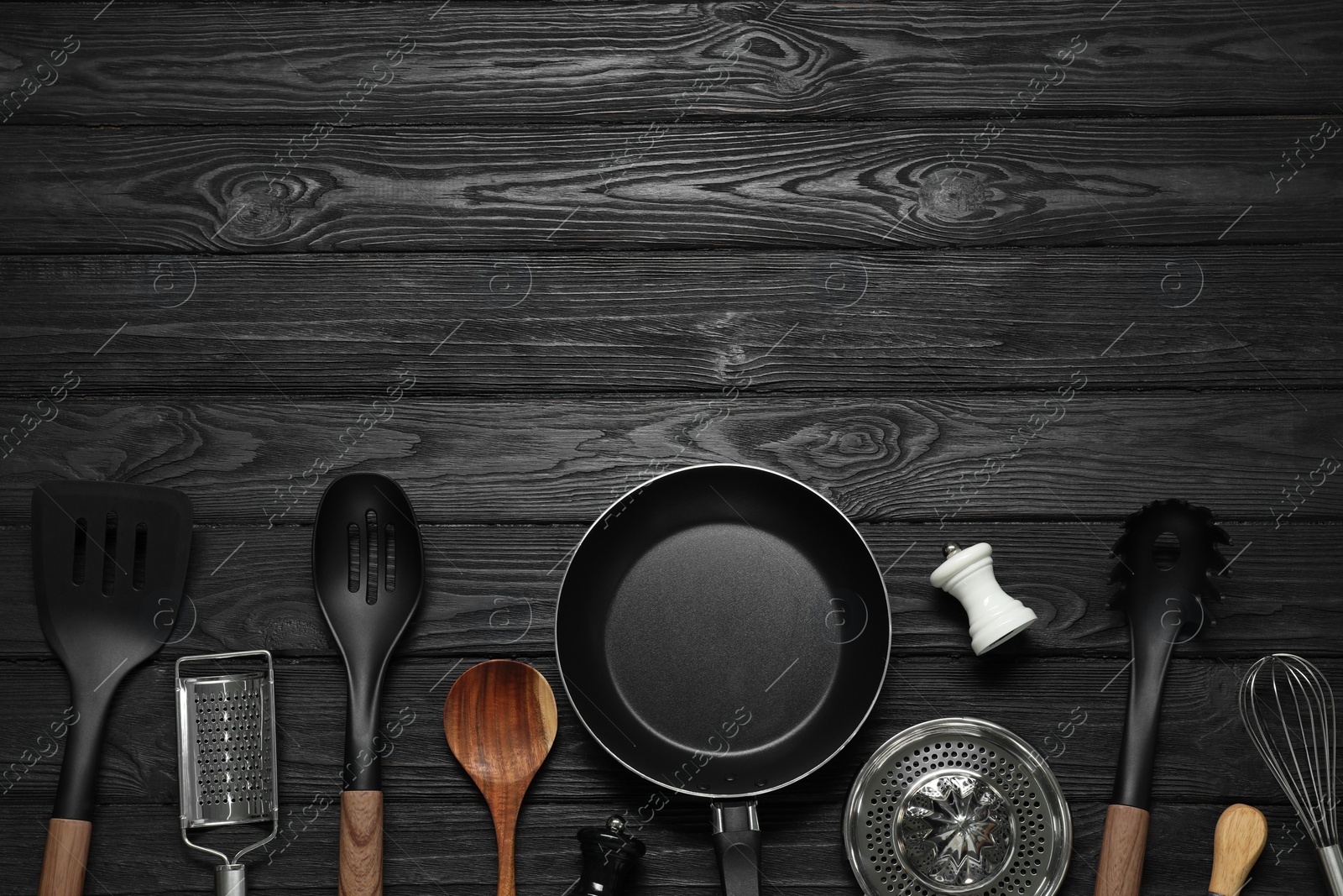 Photo of Set of different kitchen utensils on black wooden table, flat lay with space for text