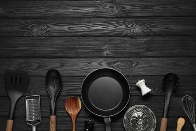 Photo of Set of different kitchen utensils on black wooden table, flat lay with space for text