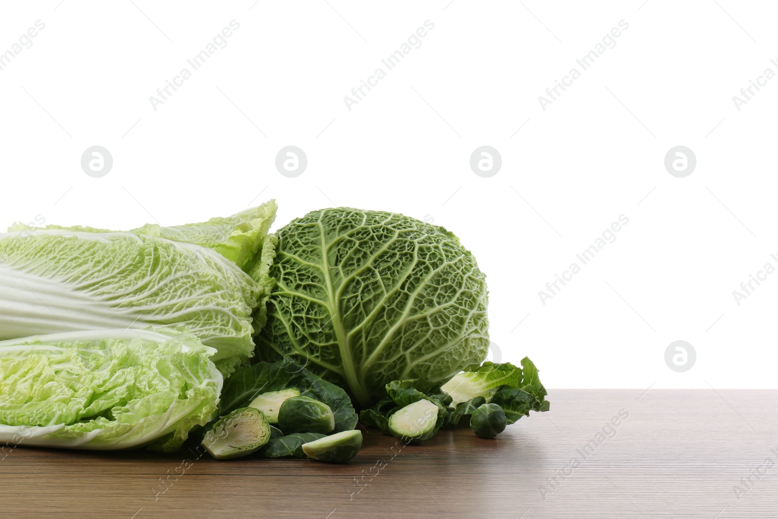 Photo of Different types of cut cabbage on wooden table against white background. Space for text