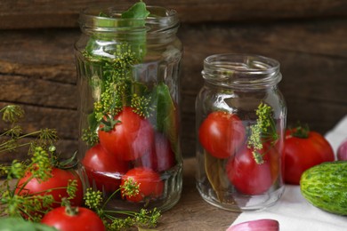 Glass jars, fresh vegetables and herbs on wooden table. Pickling recipe