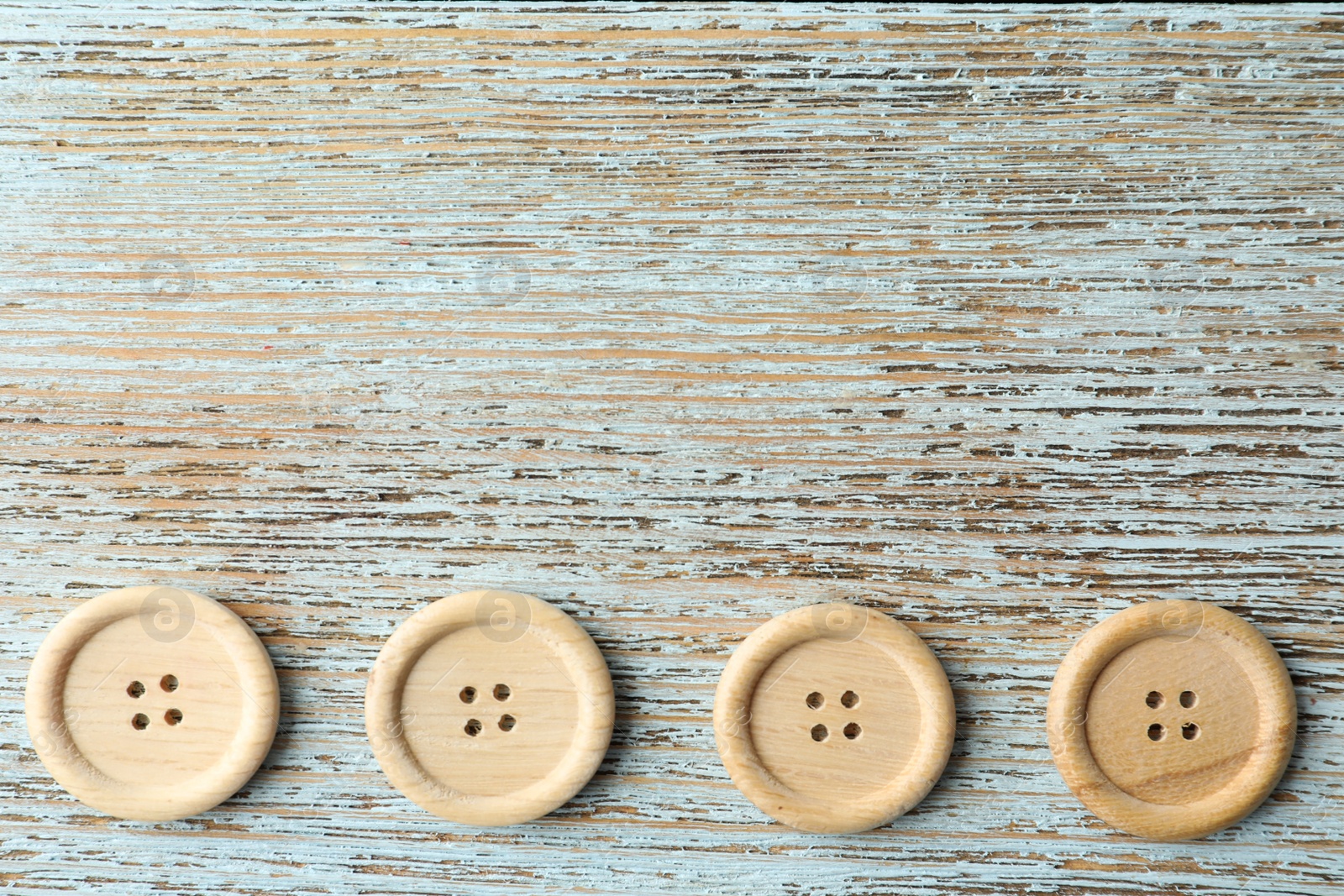 Photo of Many sewing buttons on light wooden background, flat lay. Space for text