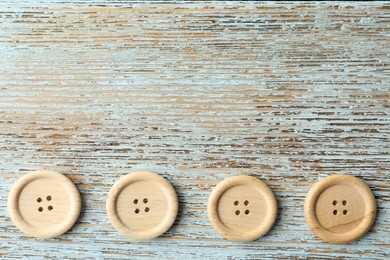 Photo of Many sewing buttons on light wooden background, flat lay. Space for text