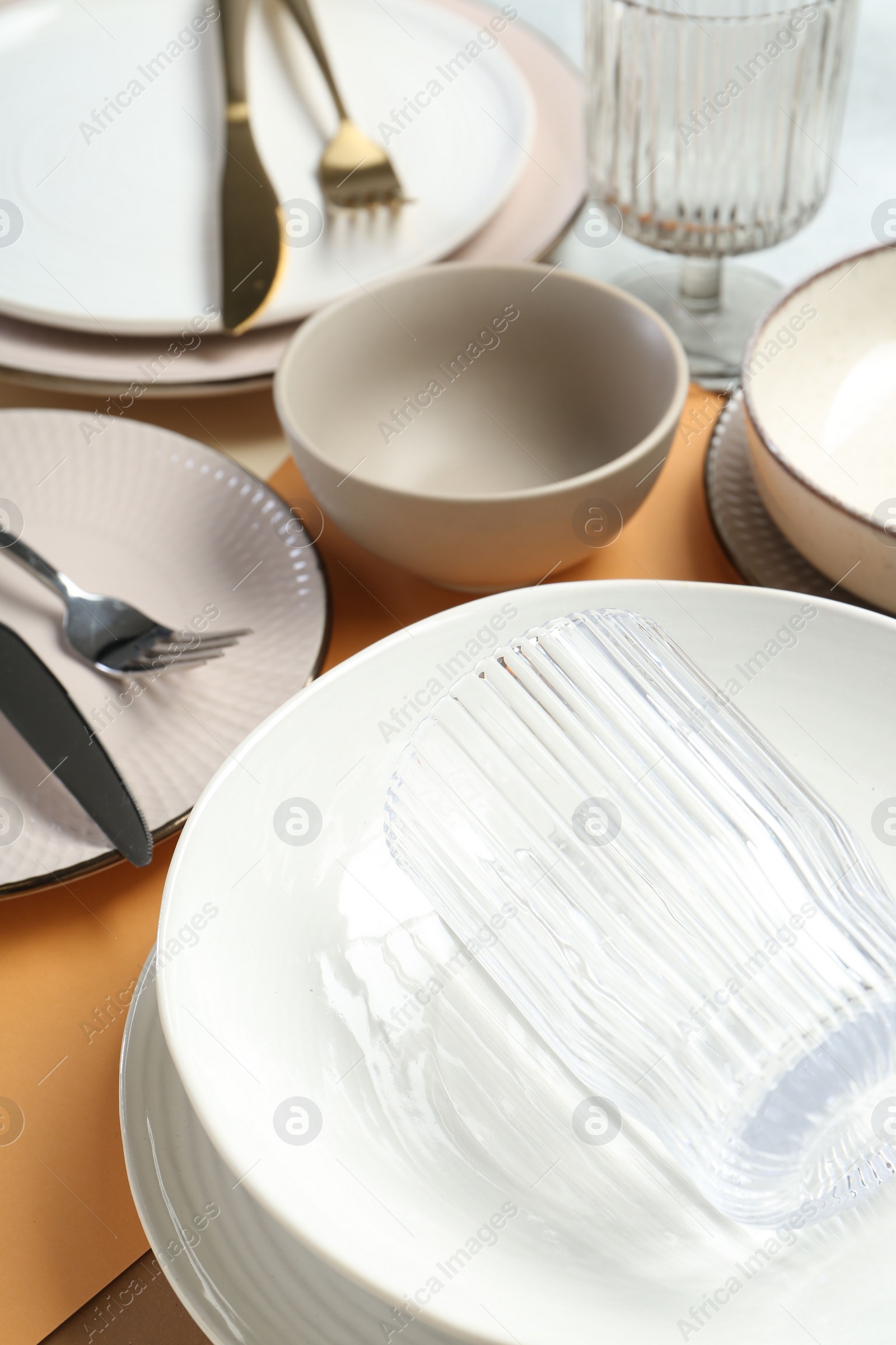 Photo of Clean plates, bowls, glass and cutlery on table