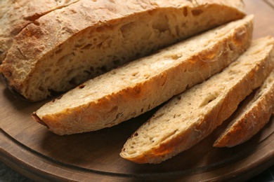 Photo of Tasty freshly baked bread on wooden board, closeup