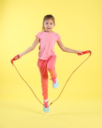 Full length portrait of girl jumping rope on color background