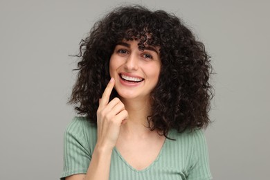 Photo of Young woman showing her teeth with whitening strip on grey background