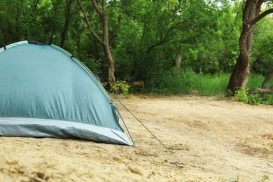 Photo of Modern camping tent in forest. Space for text